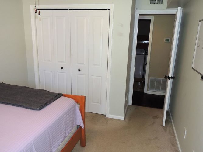 A bedroom with a bed, a wardrobe and a small fridge.