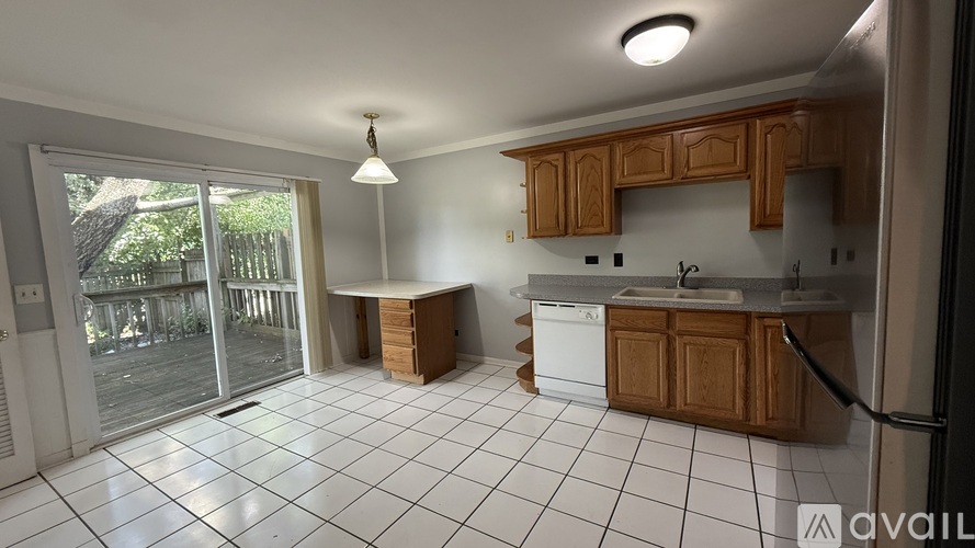 A kitchen with wooden cabinets and a white fridge is available for rent.