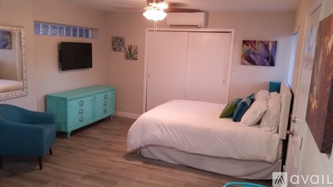 A bedroom with a white bed and a blue chair.