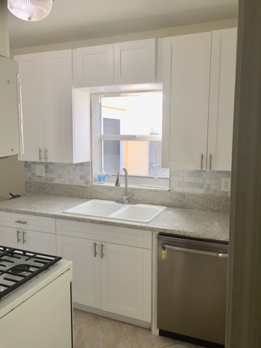 A kitchen with white cabinets and a stainless steel dishwasher.