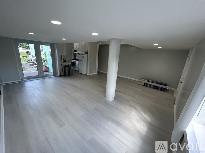 A spacious room with wooden flooring and white walls.