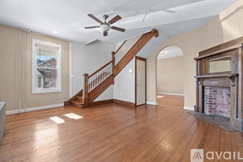 A spacious living room with wood flooring and a staircase leading to the upper level.