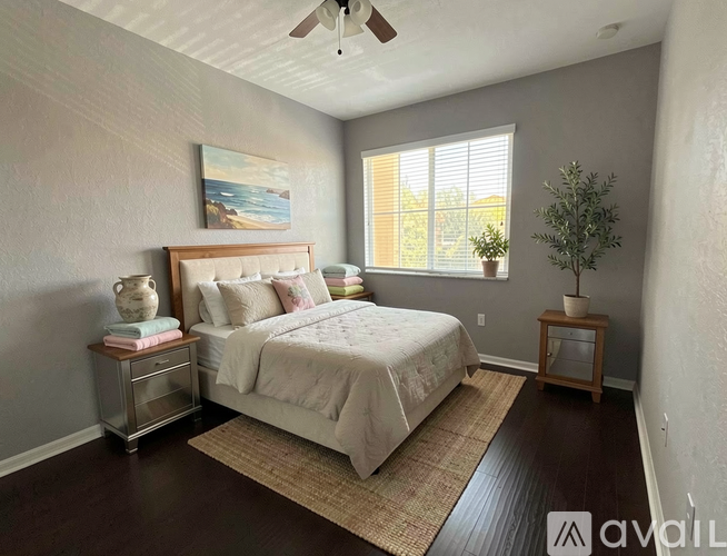 A bedroom with a bed, nightstand, and a painting on the wall.