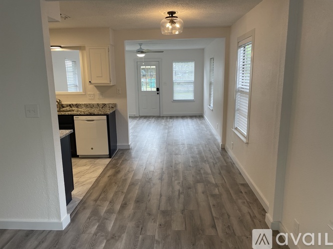 A kitchen with a white fridge and a wooden floor.