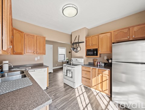 A kitchen with wooden cabinets and a stainless steel refrigerator.