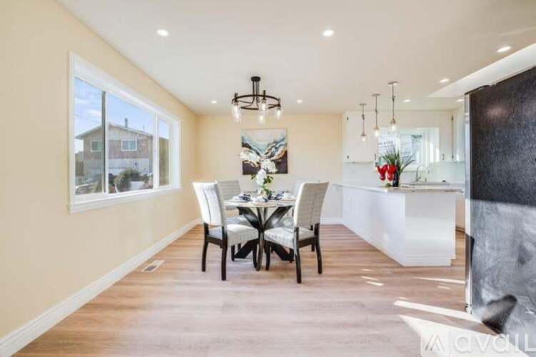 A dining room with a table set for four and a chandelier hanging from the ceiling.
