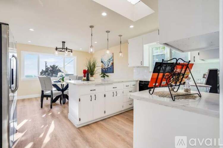 A kitchen with white cabinets and a wooden floor.
