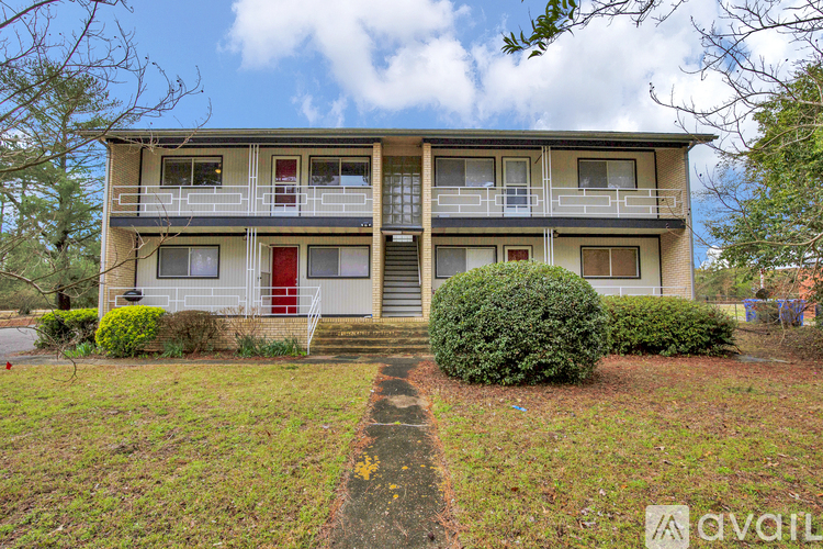 A two-story apartment building with a red door and a balcony on the second floor.