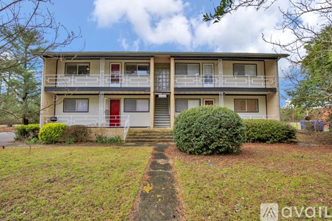 A two-story apartment building with a red door and a balcony on the second floor.
