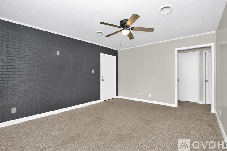 A room with a ceiling fan and a brick wall.