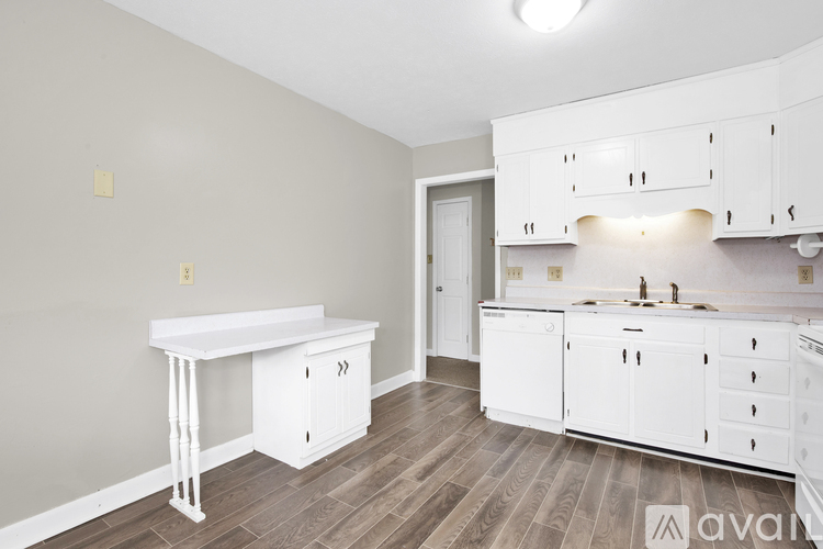 A kitchen with white cabinets and a wooden floor.