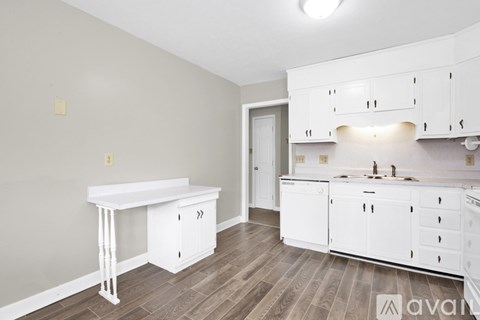 A kitchen with white cabinets and a wooden floor.