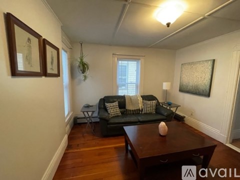A living room with a black couch and a wooden coffee table.