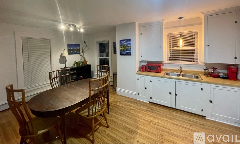 A kitchen with a table and chairs in the foreground and a painting on the wall.