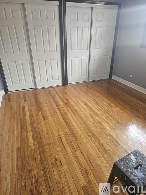 A room with wooden flooring and two white doors.