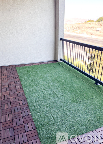 A balcony with a black railing and a green artificial grass area.