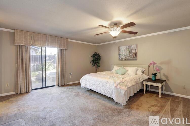 A bedroom with a large bed, a ceiling fan, and sliding glass doors.
