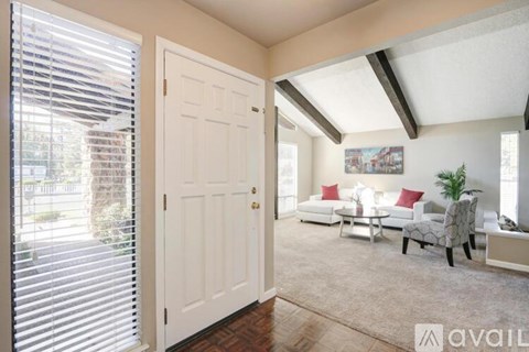 A living room with a white door and a couch with red pillows.