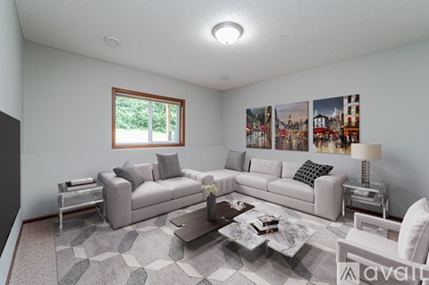 A living room with a grey sofa set, a coffee table, and a large window.
