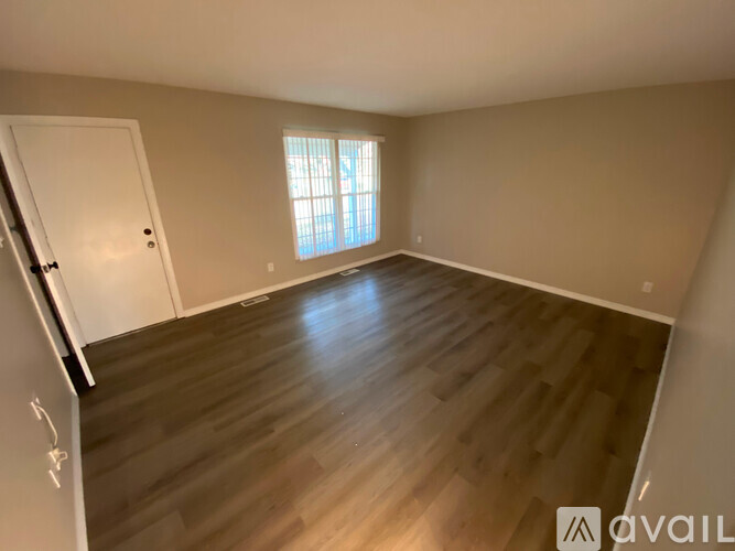 A room with wooden flooring and a window letting in natural light.