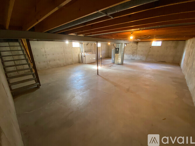 A spacious attic room with a ladder and a door.