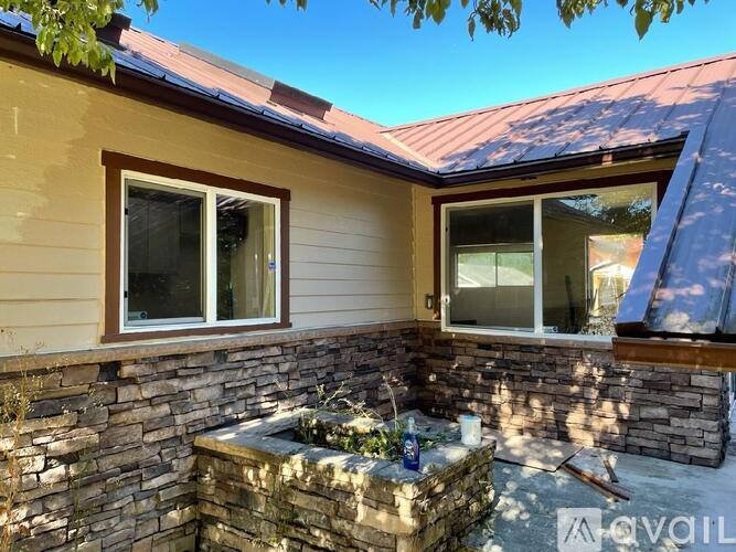 A house with a stone wall and two windows is for sale.