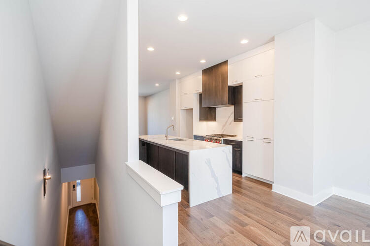 A modern kitchen with white cabinets and a wooden floor.