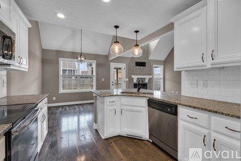 A kitchen with white cabinets and a black countertop.