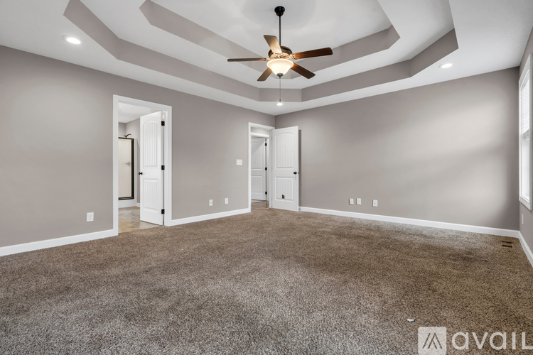 A spacious room with a ceiling fan and carpeted floor.