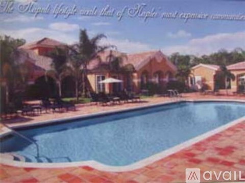 A pool surrounded by a brick border and a house in the background.
