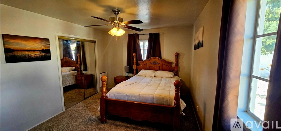 A bedroom with a large bed and a ceiling fan.