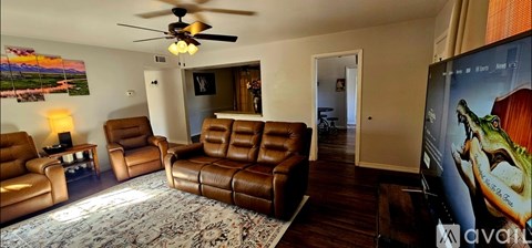 A living room with brown leather furniture and a ceiling fan.