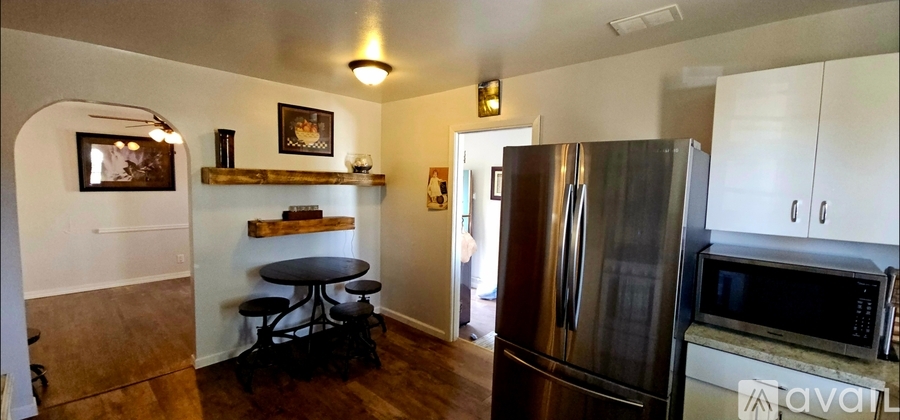 A kitchen with a stainless steel refrigerator and white cabinets.
