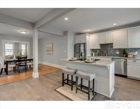 A kitchen with white cabinets and a bar stool.