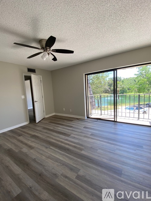 A room with a ceiling fan and sliding glass doors leading to a pool area.