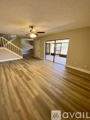 A spacious room with wooden flooring and a ceiling fan.