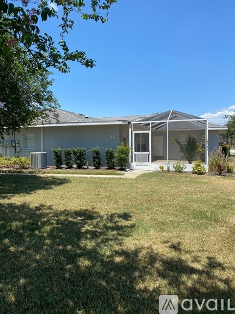 A house with a white fence and a glass door is surrounded by greenery.