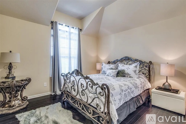 A bedroom with a large bed and a table with a lamp.