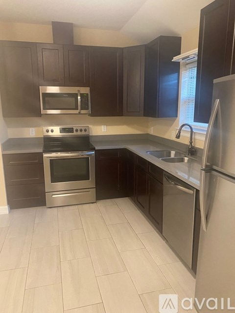 A kitchen with dark brown cabinets and stainless steel appliances.