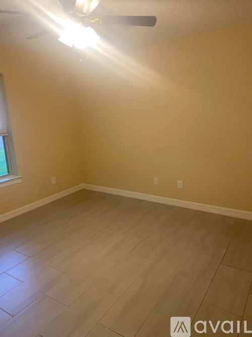 A room with a ceiling fan and light, and a window on the wall.