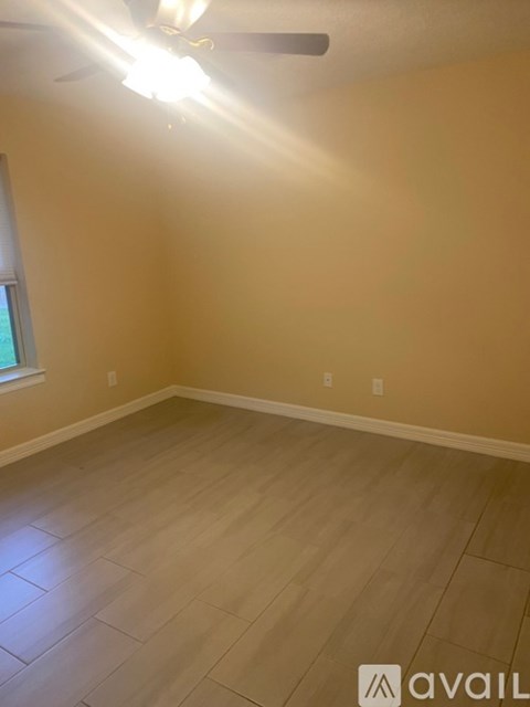 A room with a ceiling fan and light, and a window on the wall.