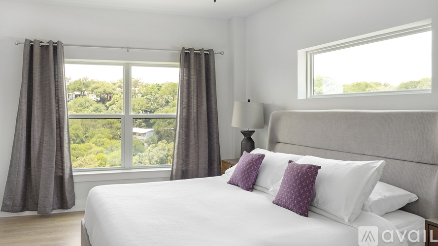 A bedroom with a large bed and a window overlooking a green landscape.