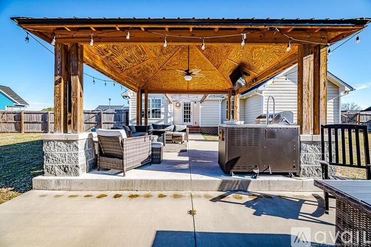 A wooden pergola with a grill under it.