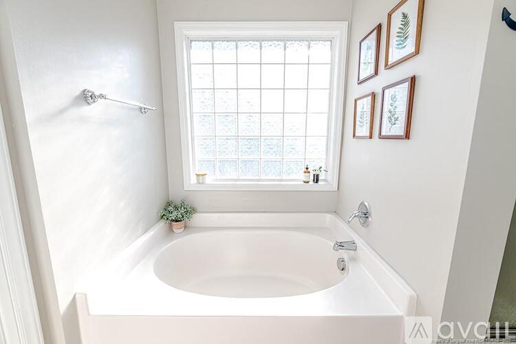 A white bathroom with a tub and a window.