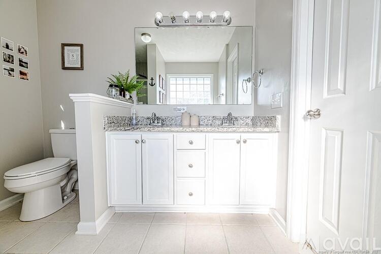 A white bathroom with a toilet, sink, and mirror.