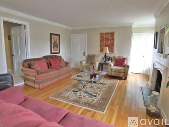 A living room with a couch, chairs, and a rug.