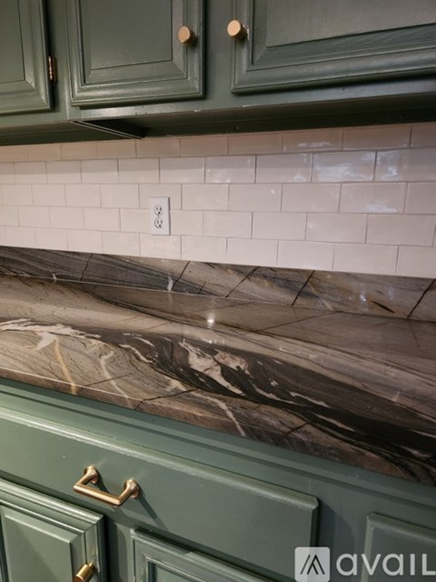 A kitchen counter with a marble top and green cabinets.