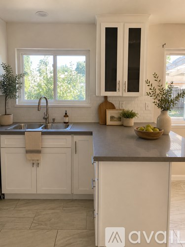 A kitchen with white cabinets and a window above the sink.