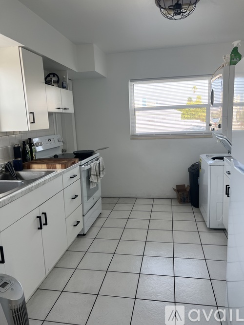 A kitchen with white cabinets and a white washing machine.