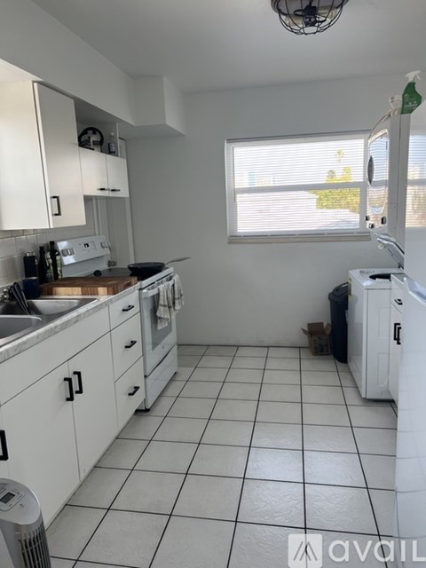 A kitchen with white cabinets and a white washing machine.